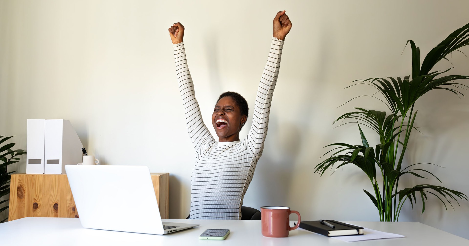 Young woman cheering at open laptop